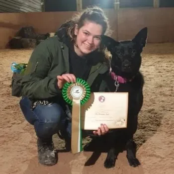 Jordan with her dog and a Good Citizen award rosette and certificate